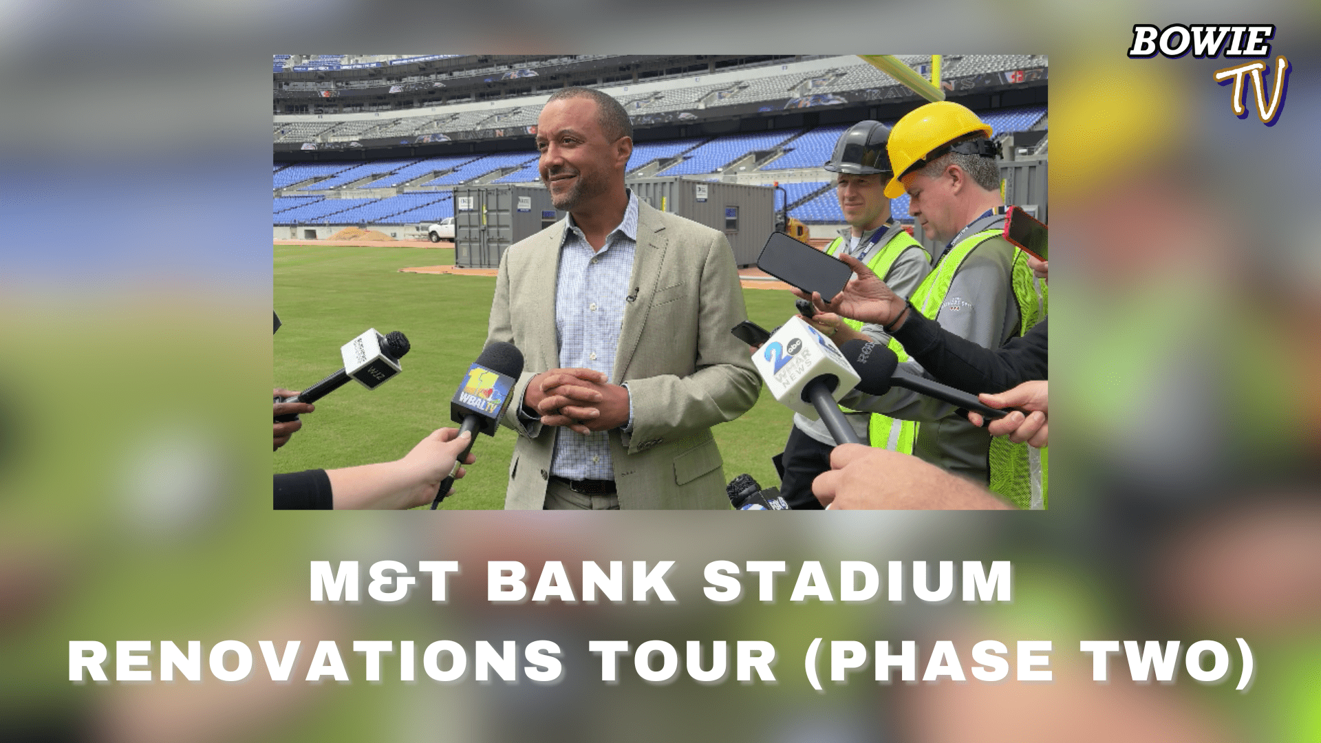 A man in a suit speaks to reporters with microphones at M&T Bank Stadium during renovations, while workers in safety vests and helmets stand nearby. Text reads: M&T Bank Stadium Renovations Tour (Phase Two) and Bowie TV.